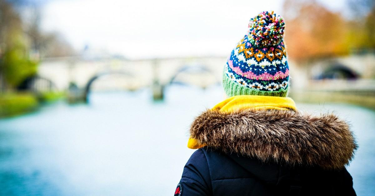 A person in a fur lined coat stands with their back to the camera