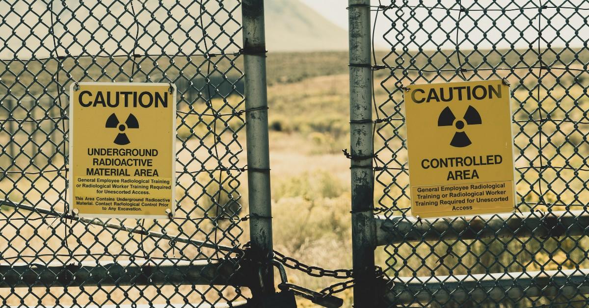 A pair of yellow signs hang on a fence warning people about radioactive material in the area