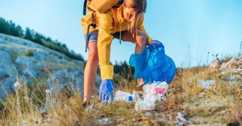 Young woman activist picking up trash in nature. (Representative Cover Image Source: Getty Images | LordHenriVoton)