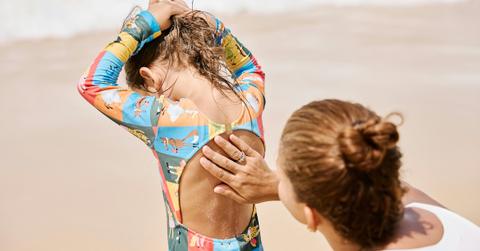 mom putting sunscreen daughter at beach
