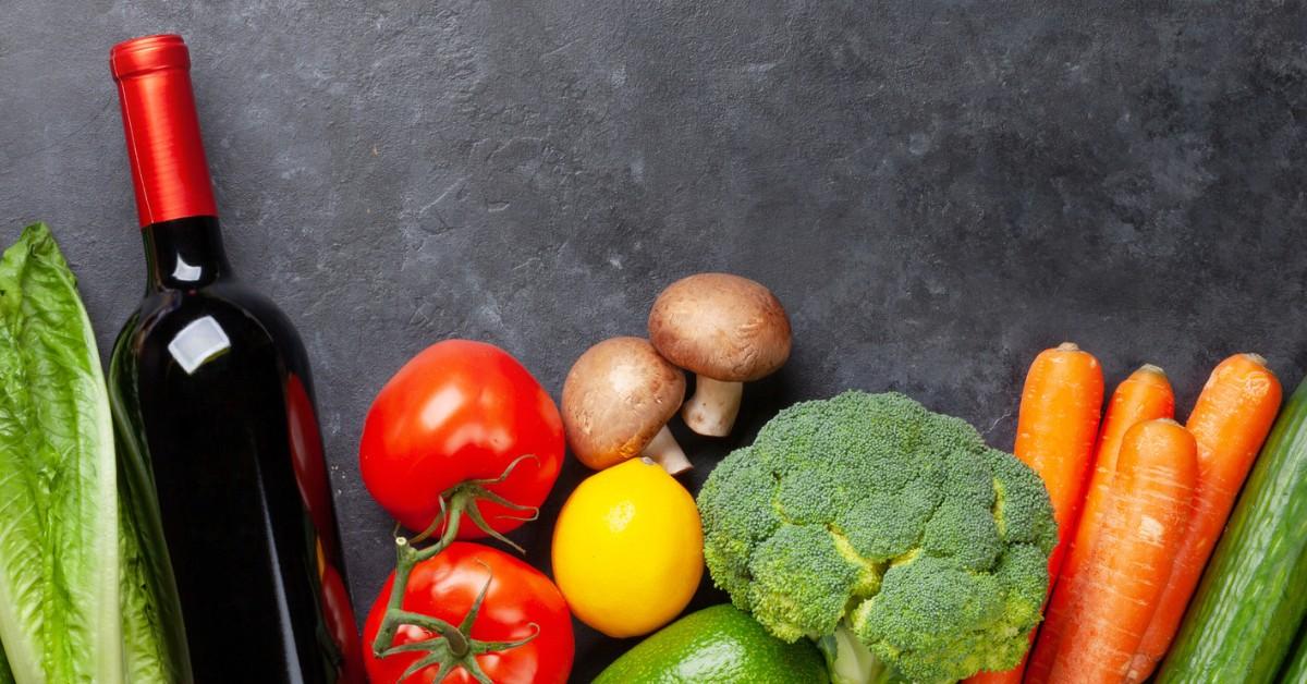 A bottle of wine surrounded by vegetables 