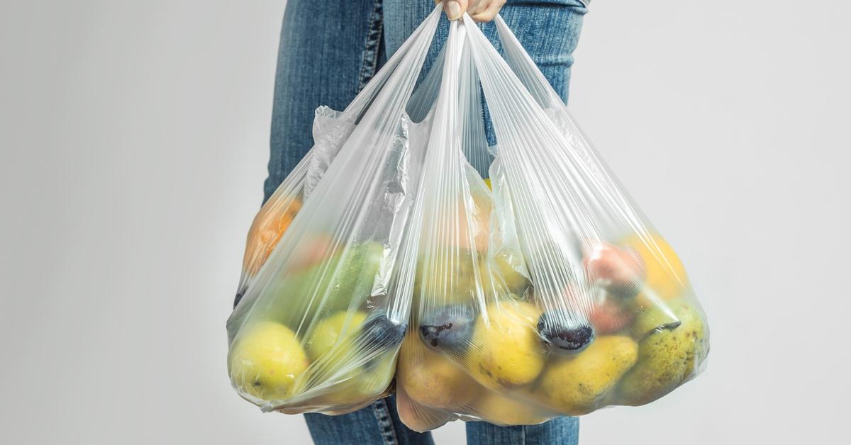 Person carrying plastic bag with fruit. 