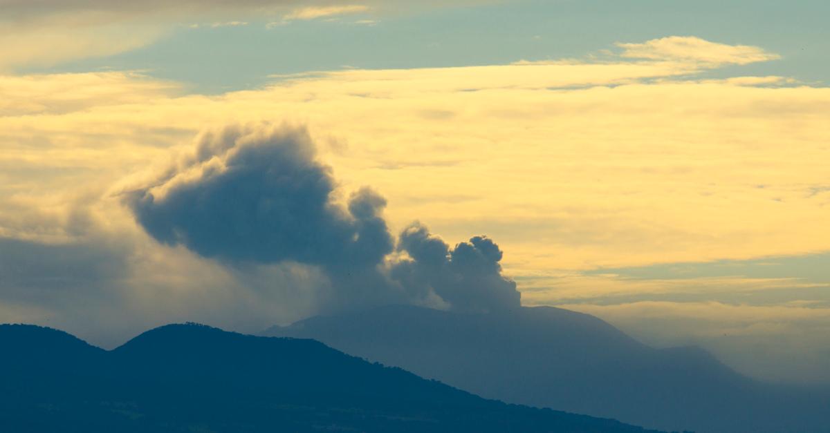 Two mountains with a smoking volcano in the distance. 