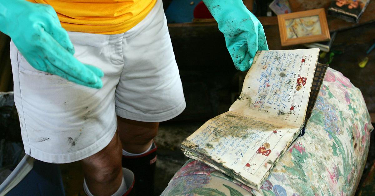 Woman wearing gloves finds moldy book in storm-ravaged New Orleans home in 2005