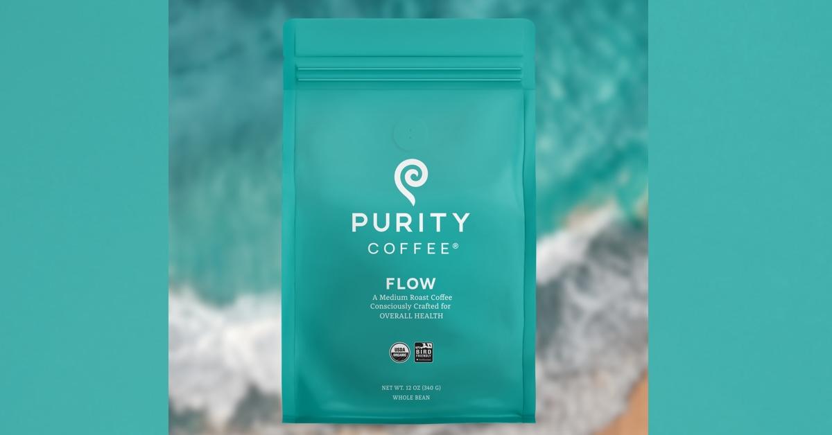 Teal bag of Purity Coffee over blurred beach 