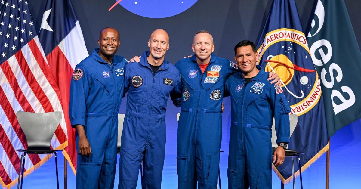 The Artemis crew poses for photos in front of the NASA logo