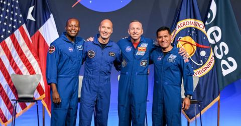The Artemis crew poses for photos in front of the NASA logo