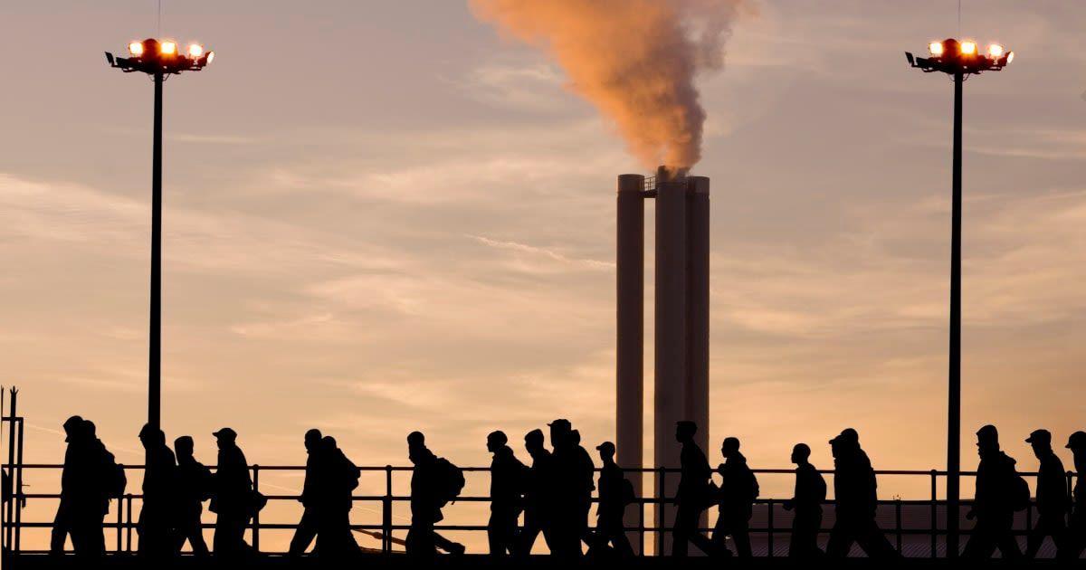People walk by as thick smoke emanates from industrial chimneys. (Representative Cover Image Source: Getty Images | sculpies)