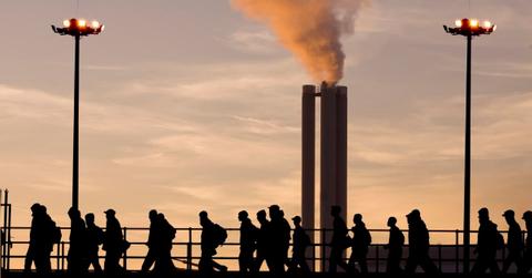 People walk by as thick smoke emanates from industrial chimneys. (Representative Cover Image Source: Getty Images | sculpies)