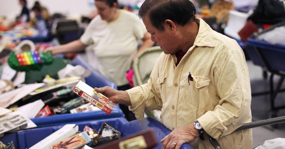 Man looks at VHS tapes in blue bins at a Goodwill