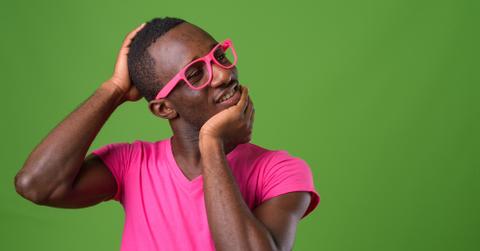 A man cracking his neck against a green background.