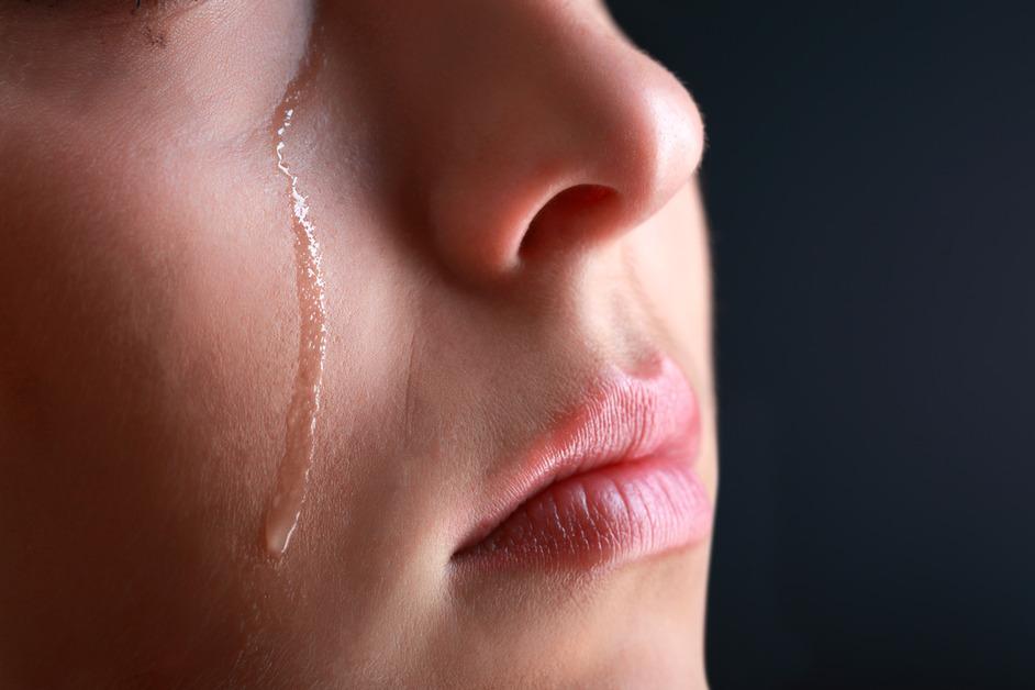 A close. up photo of a tear rolling down a person's cheek. 