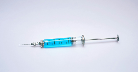 A syringe of blue liquid sits against a white background