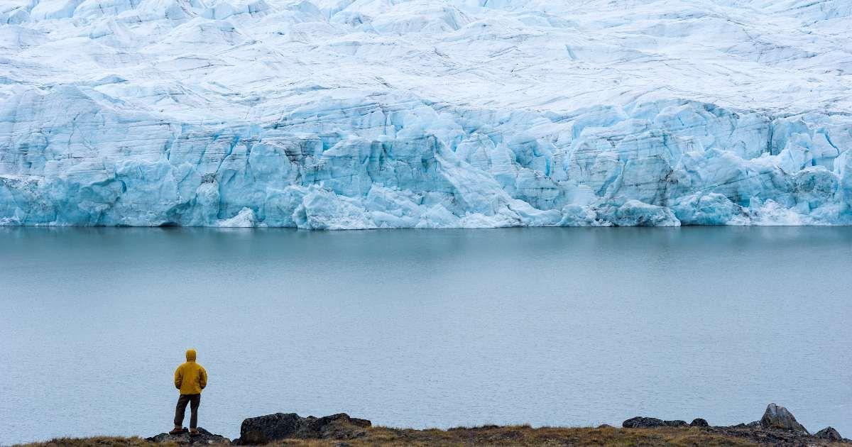 A hiker dwarfed by the fracture zone of a glacier on the Greenland Ice Sheet. (Representative Cover Image Source: Getty Images | Jason Edwards)