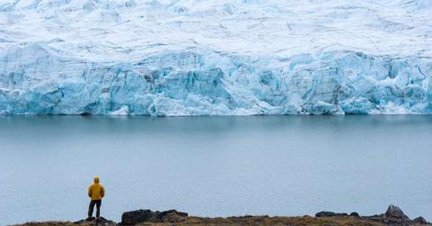 A hiker dwarfed by the fracture zone of a glacier on the Greenland Ice Sheet. (Representative Cover Image Source: Getty Images | Jason Edwards)
