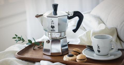 Product photo of the Bialetti Moka Pot on a serving tray beside a mug and cookies