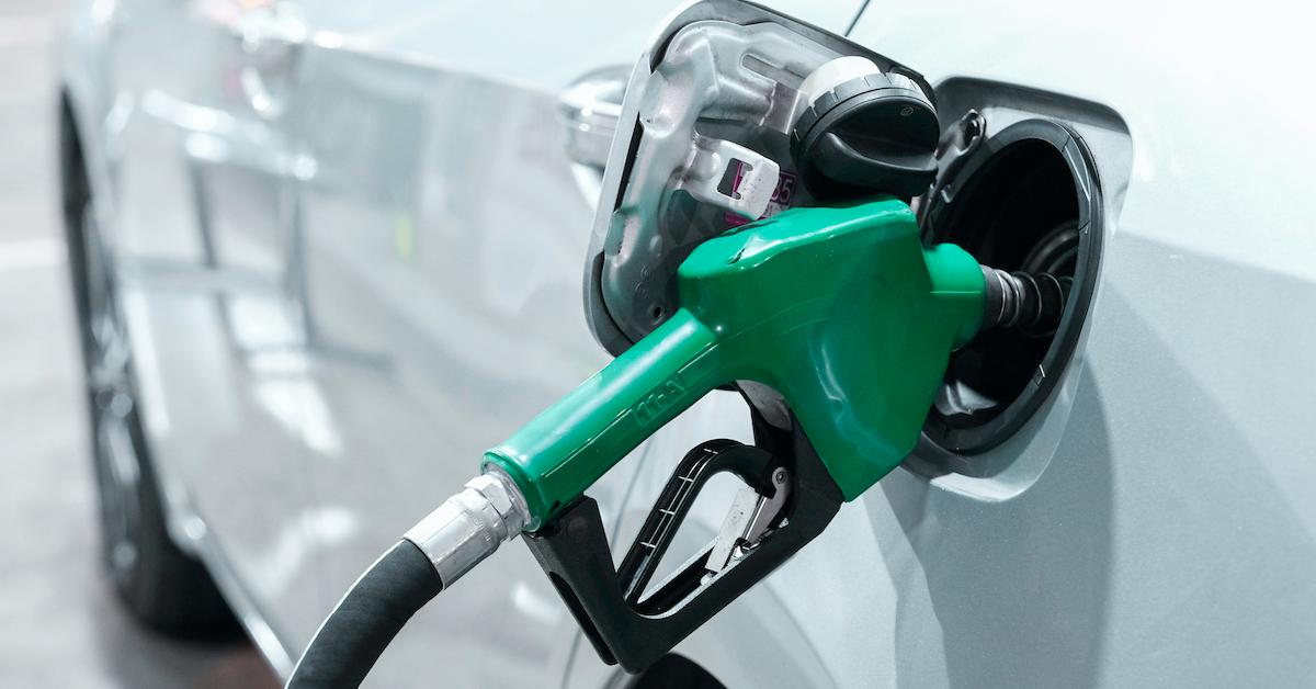 A green gas nozzle pouring fuel into a car.