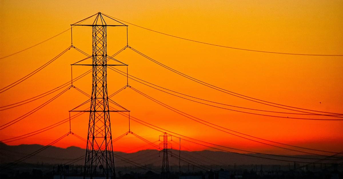 An series of electrical lines appear against an orange sunset