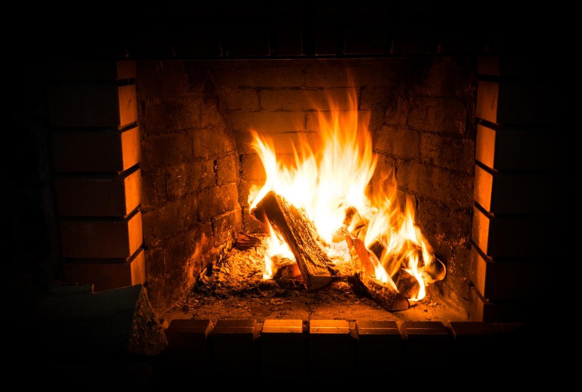 Fire burning in wood-burning fireplace surrounded by brick