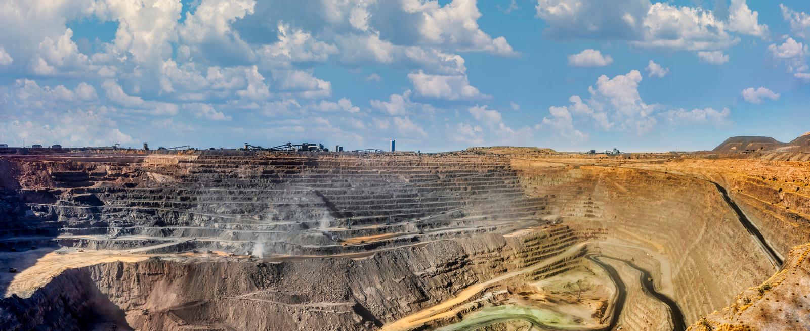 A wide angle view of a diamond mining pit on a partially cloudy day. 