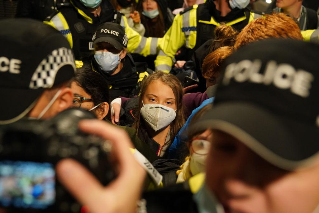 Greta Thunberg is surrounded by police officers as she arrives at Glasgow Central train station, rather than by plane, before COP26 in October 2021.