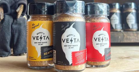 Three bottles of Benny T's Dry Hot Sauce on a wooden table