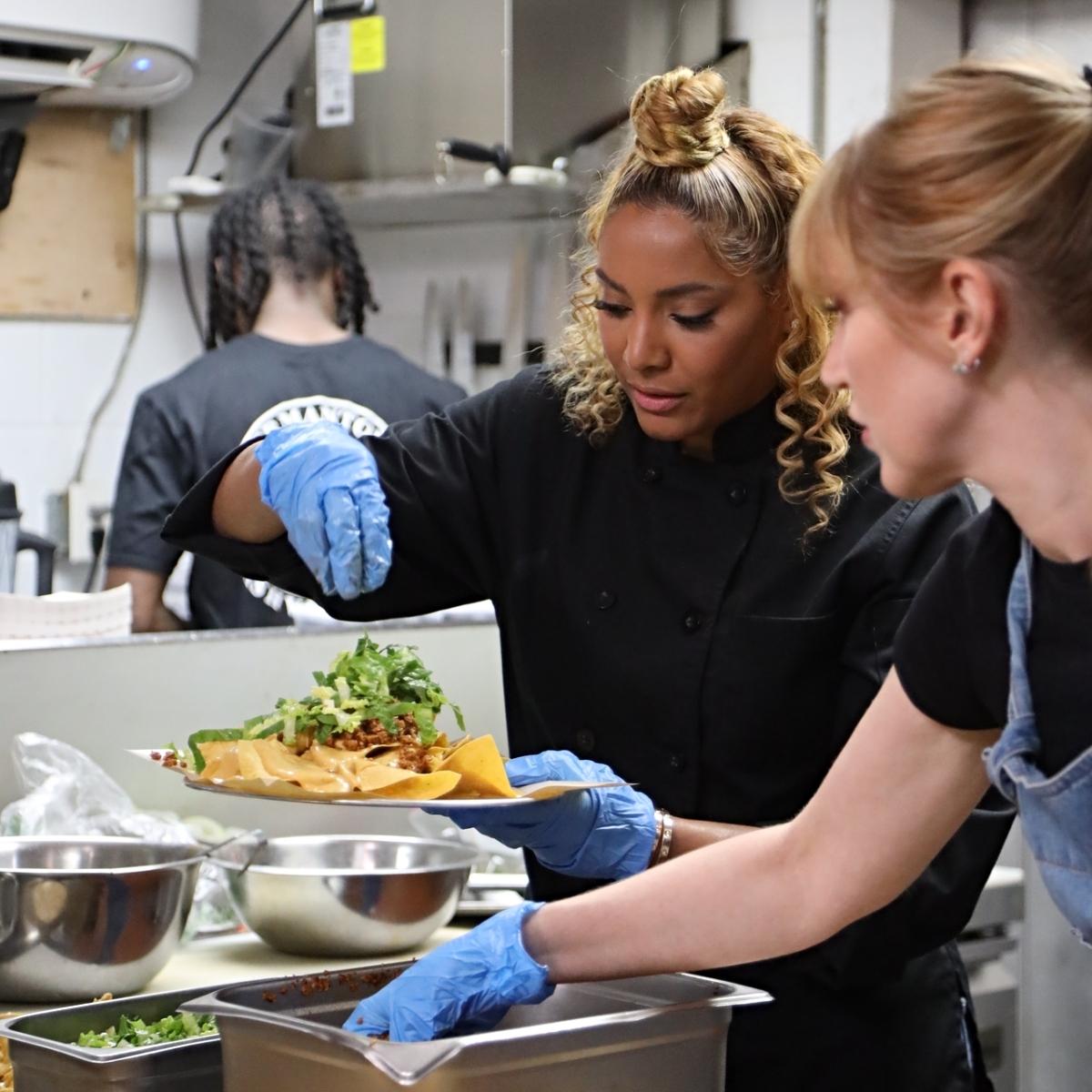 Photo of Chef Charity Mrgan adding toppings to vegan pub chips in Max special 'Unbelievably Vegan With Chef Charity'