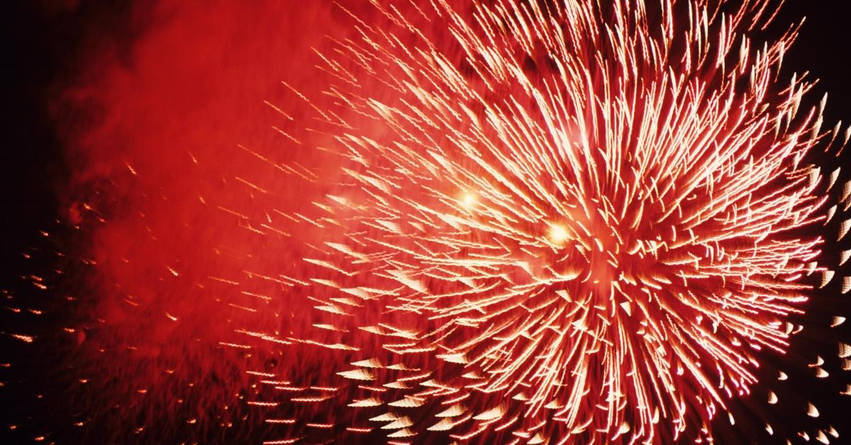 A burst of red fireworks in a night sky.