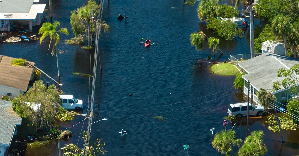 Flooded neighborhood after hurricane in Florida with person kayaking through.