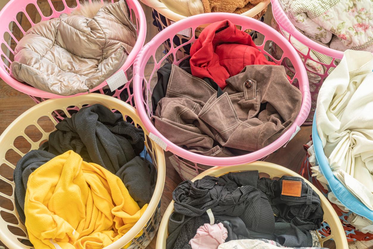 Various colored laundry baskets full of different kinds of clothing.