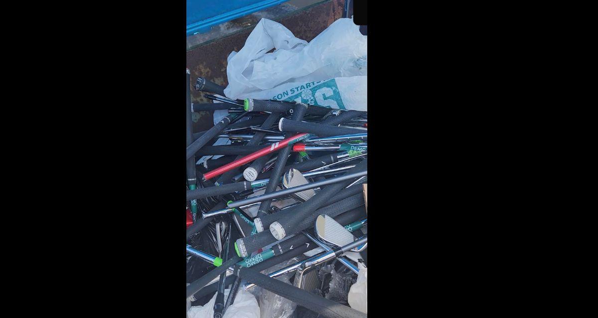 Broken golf clubs in a dumpster. 