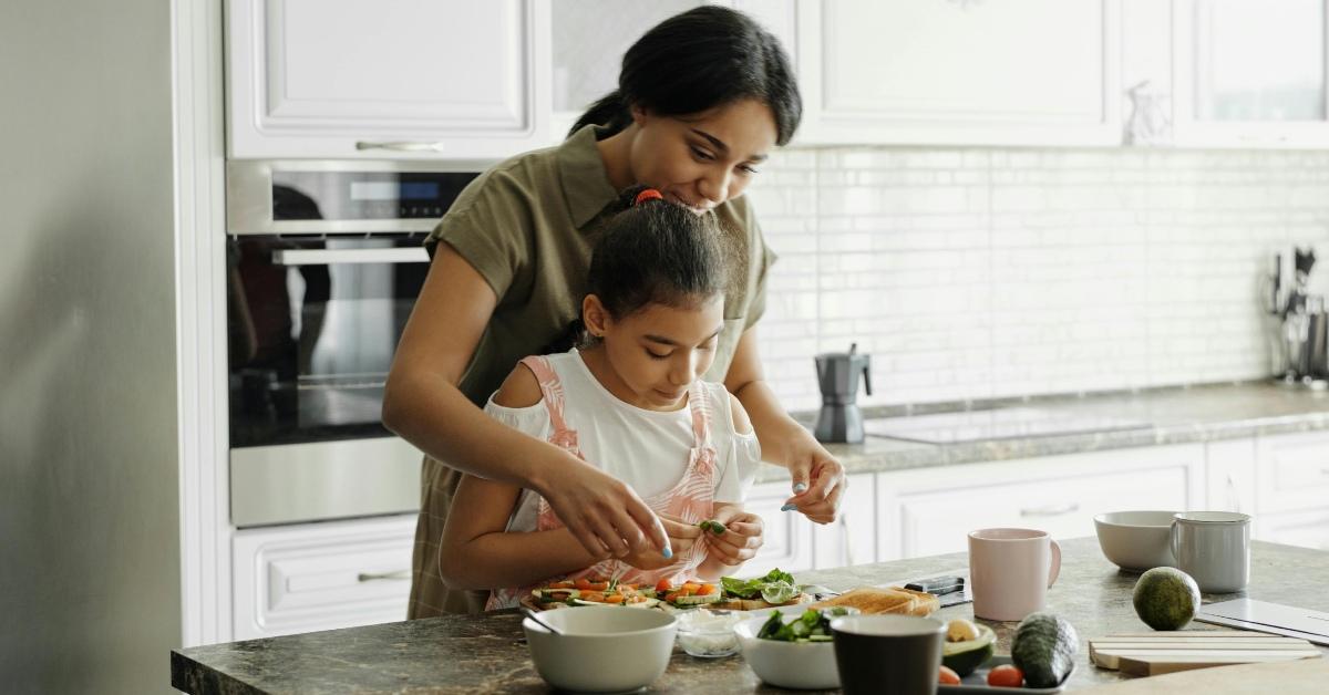 A child helps her mom prepare a meal.