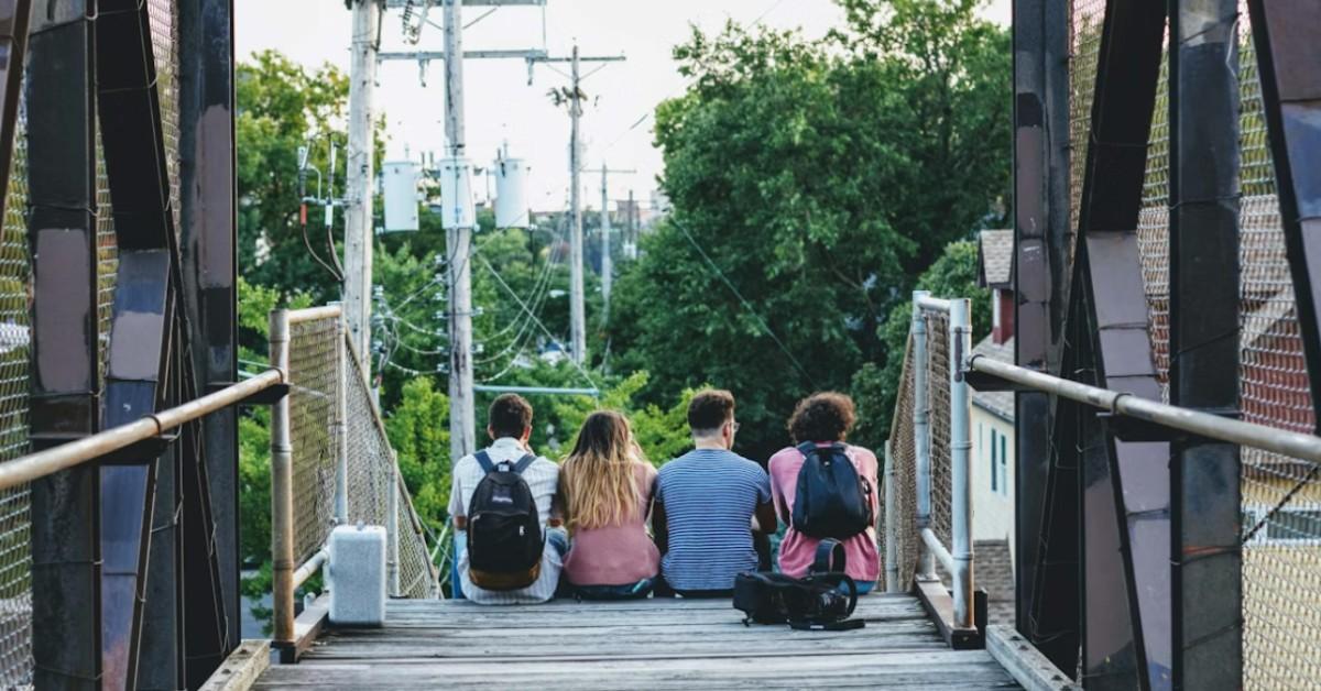 Teens sit on a bridge together