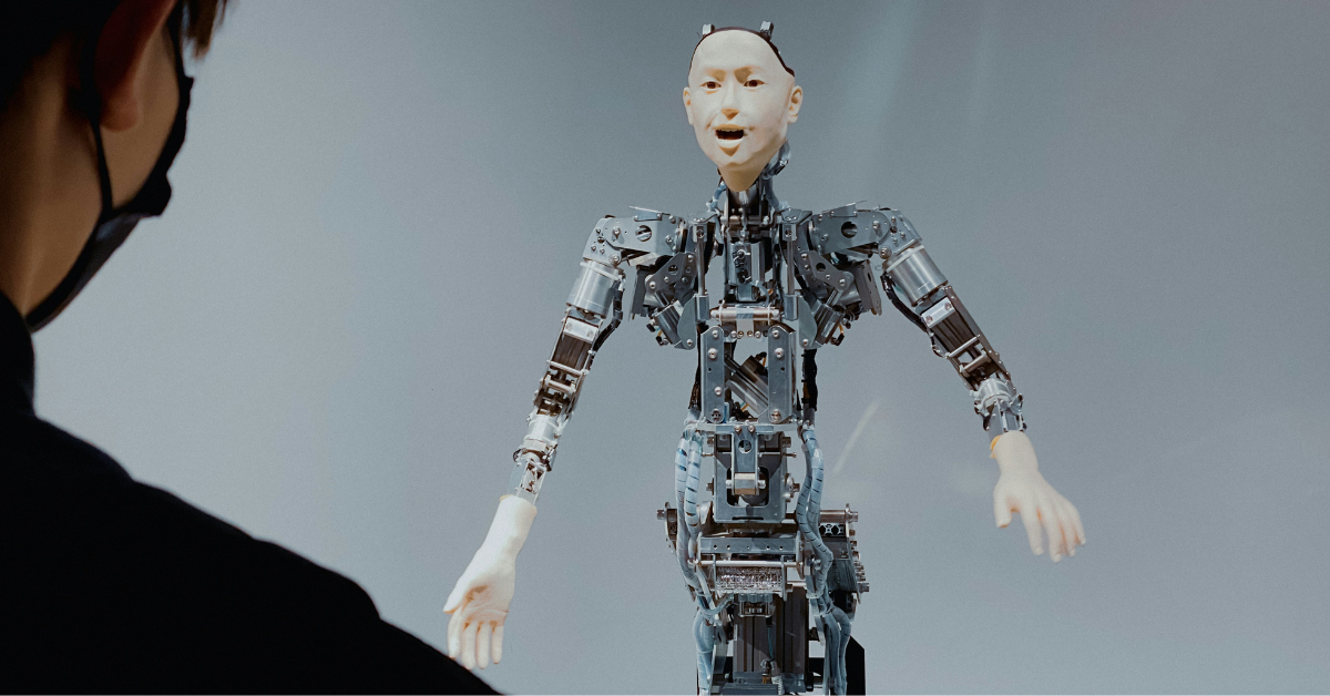 A robot with a human face stands in front of a man