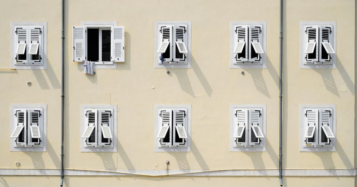 Several windows along the side of a building stand open