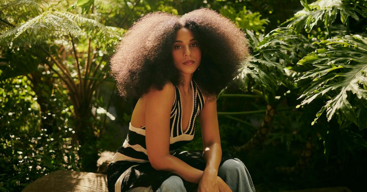 Woman with afro poses in a garden