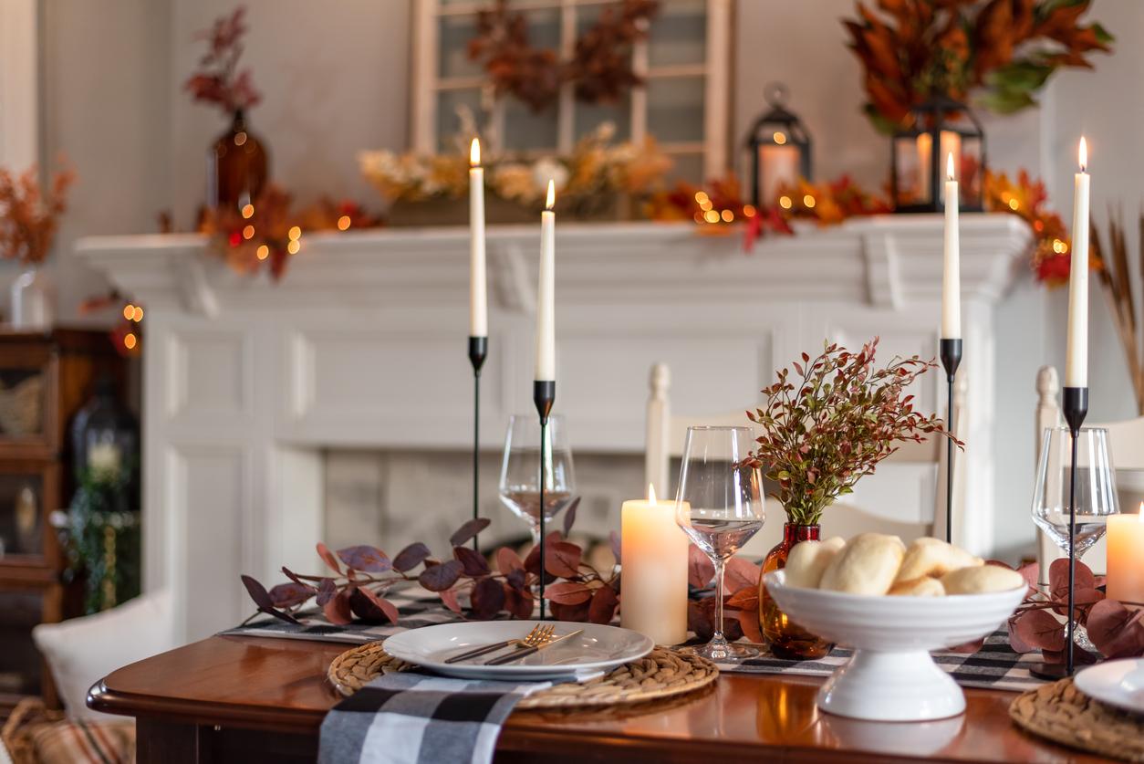 A table is set with Thanksgiving decorations, including plants and candles.