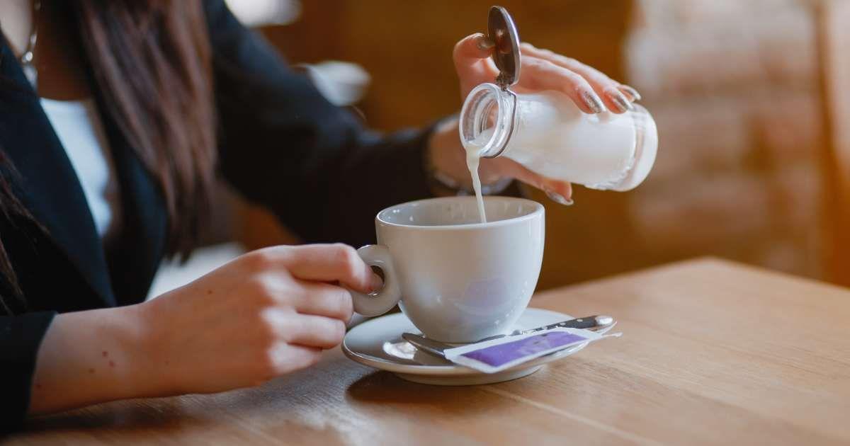 A woman is pouring coffee creamer into a cup of espresso. (Representative Cover Image Source: Freepik | Prostooleh)
