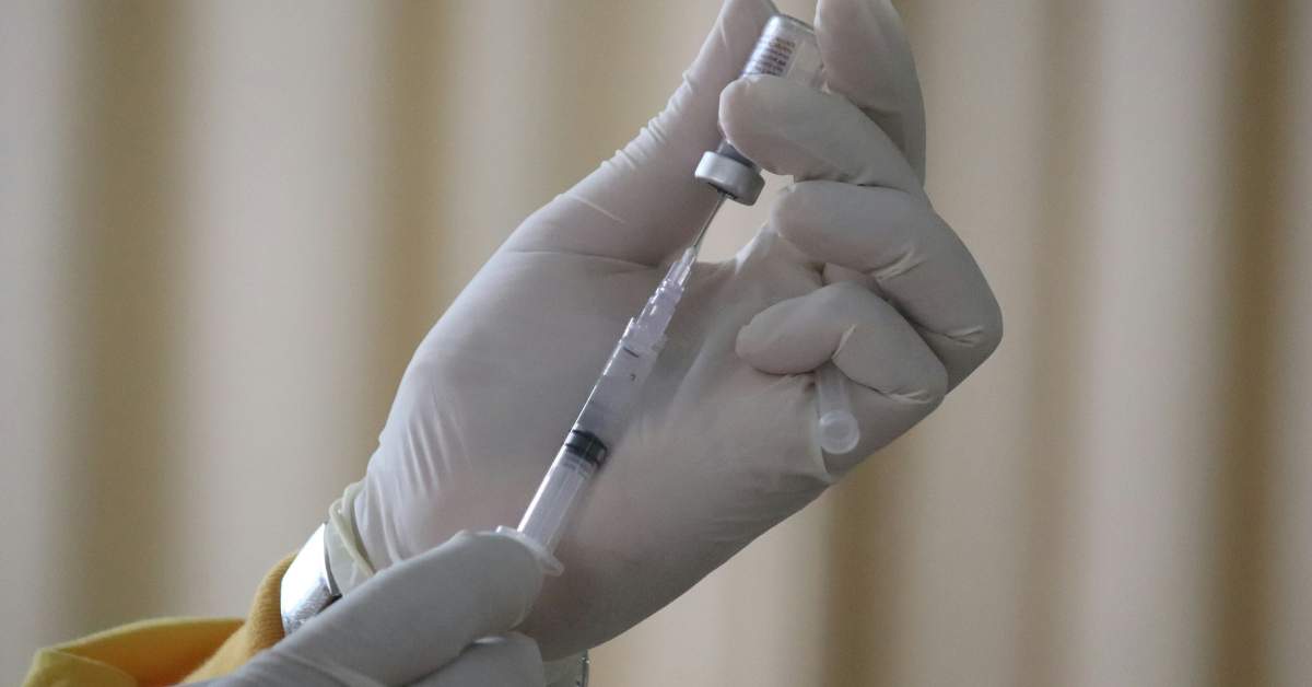 A person uses a syringe to empty a vile