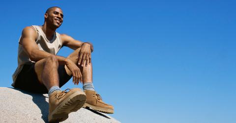 Man sitting on a rock, with hiking boots.