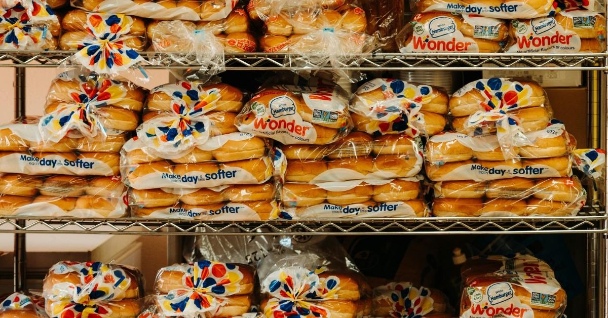 A metal shelf holds several rows of bagged Wonder bread