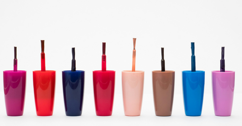 A collection of nail polish lids are lined up against a white background