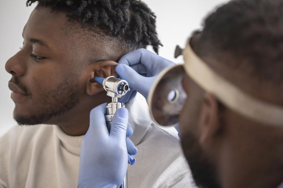 Close-up of doctor checking patient's ear. 