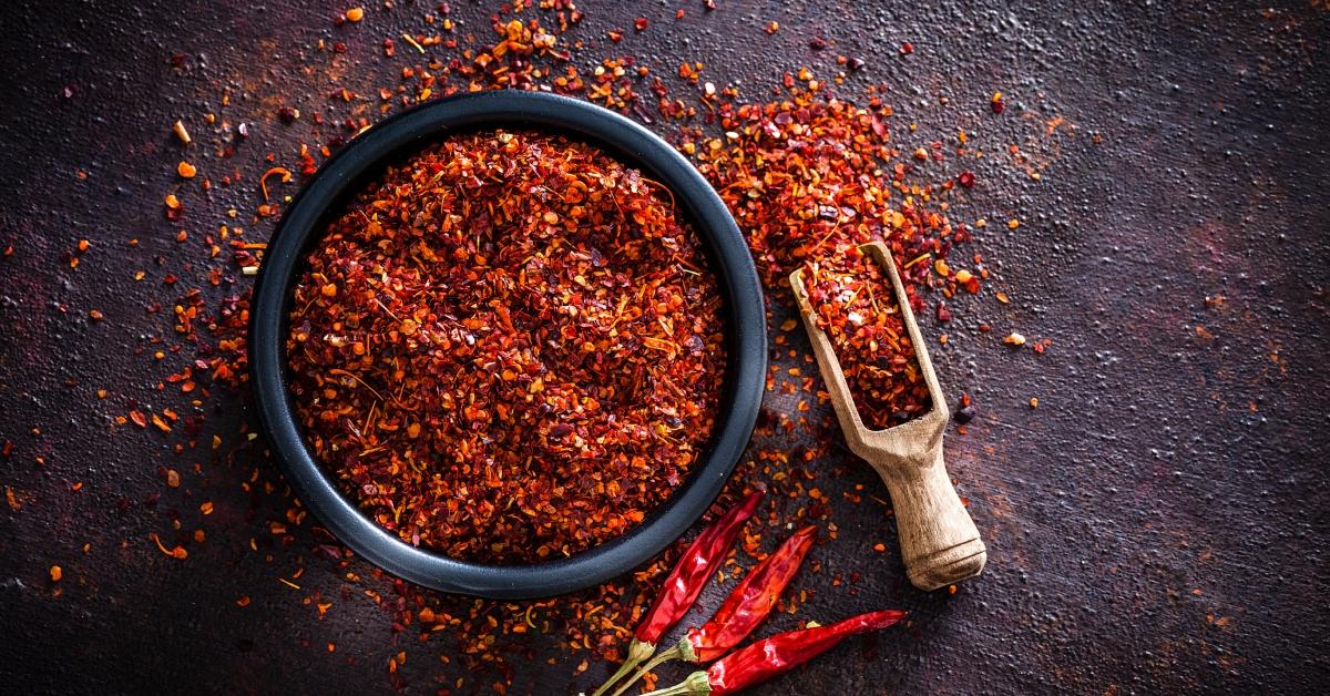 An overhead photo of a bowl of chili spice and a wooden spoon.