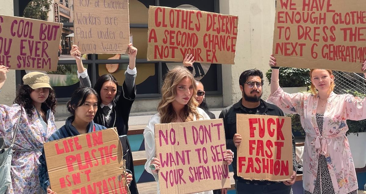 Protesters wearing robes hold up signs at Shein protest