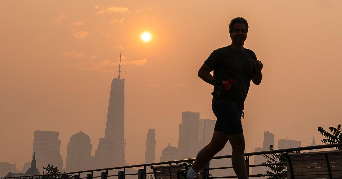 Person running near the One World Trade Center as the smoke from the Canadian wildfires paints the sky orange.