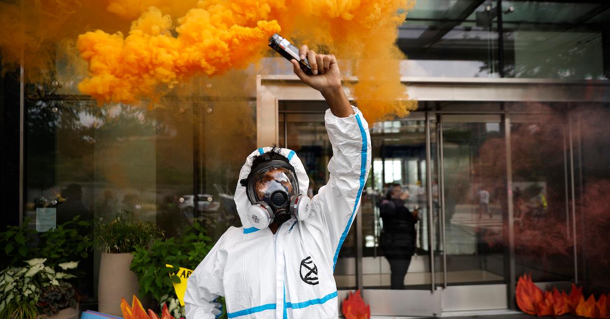 A member of Extinction Rebellion Washington wears a gas mask and holds up an orange device on July 8, 2022 in Washington, D.C. 