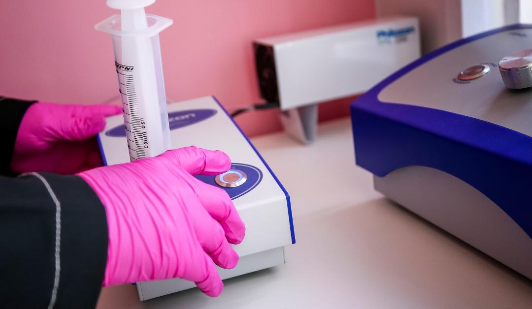 A nurse prepares ozone for application in her office wearing pink gloves