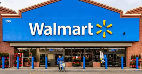 A woman pushes a shopping cart in front of a Walmart store
