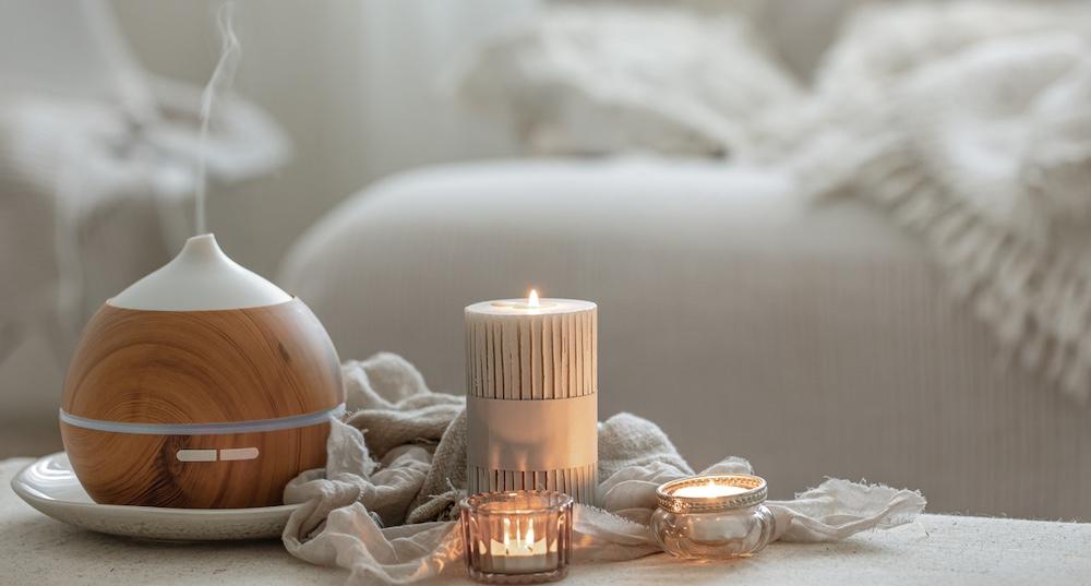 A diffuser on a tray alongside candles in a bedroom. 